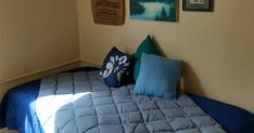 a bed with blue sheets and pillows in a room next to pictures on the wall