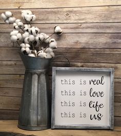 a metal vase with cotton in it next to a sign that says, this is real love