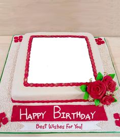 a square birthday cake with white frosting and red flowers on top, sitting on a table