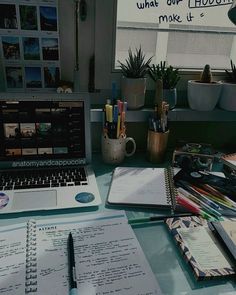 an open laptop computer sitting on top of a desk next to a notebook and pen