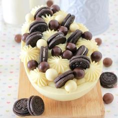 an oreo cookies and cream cake on a cutting board with chocolate chips around it