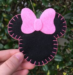 a hand holding up a black and pink minnie mouse head with a bow on it