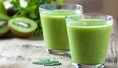 two glasses filled with green smoothie next to sliced kiwi