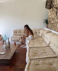 a woman sitting on top of a couch in a living room next to a coffee table