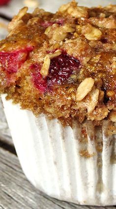 a muffin with cranberry topping sitting on top of a wooden table