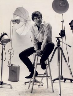 a man sitting on a stool in front of a camera