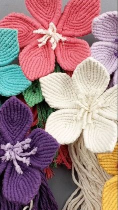 several knitted flowers are shown in different colors and sizes, including pink, yellow, purple, green, blue, and white