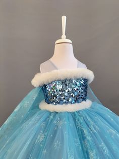 a dress with blue and white sequins on the top, sitting on a mannequin