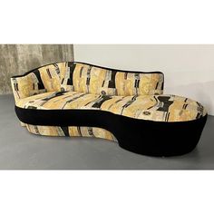 a black and yellow couch sitting on top of a cement floor next to a wall