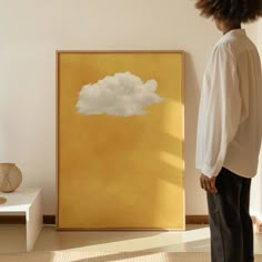 a person standing in front of a painting with a cloud painted on the wall next to it