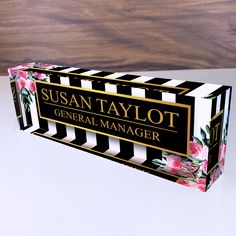 a black and white striped box with pink flowers on the side that says susan taylor general manager