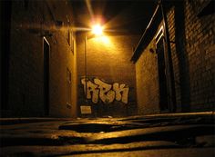 an alleyway at night with graffiti on the wall