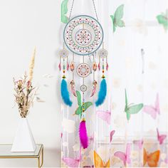 a window curtain with a dream catcher hanging from it's side next to a plant