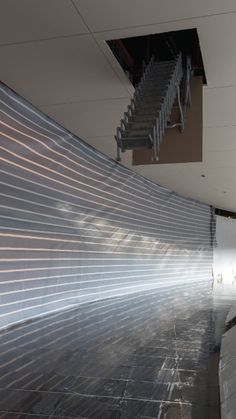 an empty room with stairs leading up to the ceiling and light shining on the wall