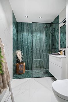 a bathroom with green tiles and a white toilet next to a walk - in shower