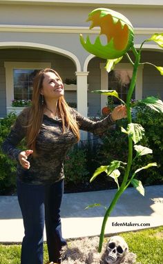 a woman standing next to a fake sunflower