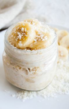 a jar filled with banana slices and oatmeal on top of a white plate