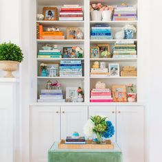 a living room filled with lots of books on top of a book shelf next to a green bench