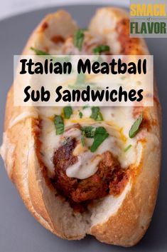 a meatball sub sandwich with cheese and herbs on it, sitting on a plate