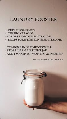 a hand holding a jar of laundry booster on top of a white wall with instructions for how to use it