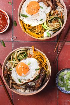 two bowls filled with food on top of a red tile floor next to chopsticks