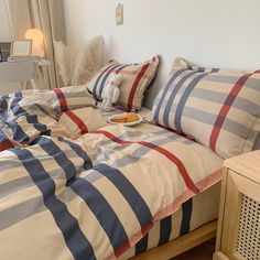 an unmade bed with blue, red and white plaid comforter in a bedroom