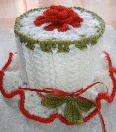 a white crocheted pot holder with red and green trimmings on it