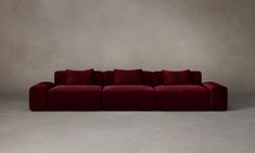 a red couch sitting on top of a white floor next to a gray wall with no one in it