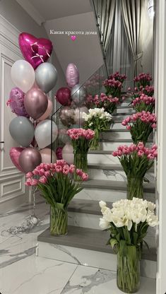 there are many vases with flowers and balloons on the stairs in front of them