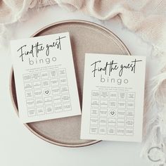 two wedding seating cards sitting on top of a plate