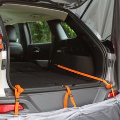 the back end of a car with an open hatchback door and orange straps on it