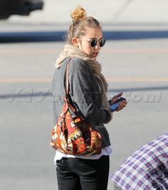 a woman is walking down the street while looking at her cell phone