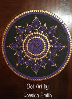 a wooden table topped with a purple and gold painted doily on top of it