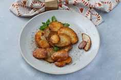 a white plate topped with fried potatoes on top of a blue table cloth next to a wooden block