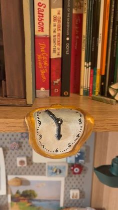 there is a clock on the shelf in front of some books and other things that are behind it