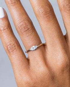 a woman's hand with a white manicured nail and an oval shaped diamond ring