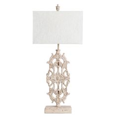 a white table lamp with a white shade on it's base and an ornate design