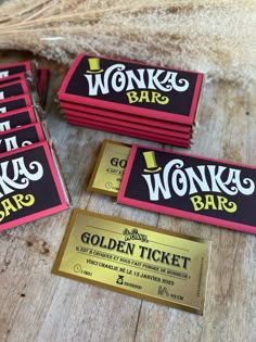 four golden ticket cards sitting on top of a wooden table next to a pile of burlocks