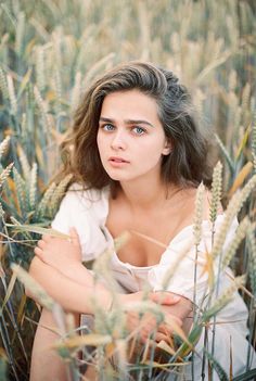 a woman sitting in tall grass with her arms crossed