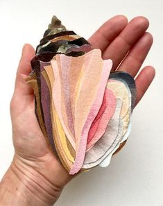 a person's hand holding several different colored pieces of cloth on top of each other