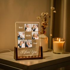 a glass photo frame sitting on top of a table next to a candle