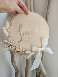 a person holding a wooden sign with the word love on it and some branches in front of them