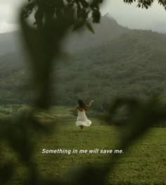 a woman in a white dress standing on top of a lush green field under a cloudy sky