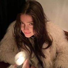 a woman sitting at a table with a light in her hand