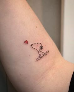 a small tattoo on the arm of a woman with a dog and heart in it