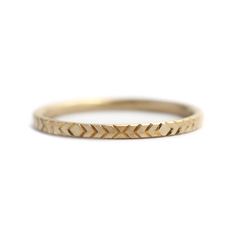 a gold ring with an arrow pattern on the side and a thin band around it