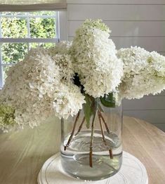 white flowers are in a glass vase on a table