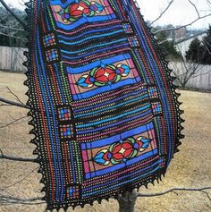 a crocheted blanket hanging from a tree in the yard with no leaves on it