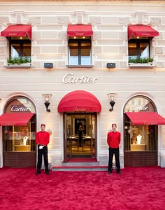 two men standing in front of a building with red awnings