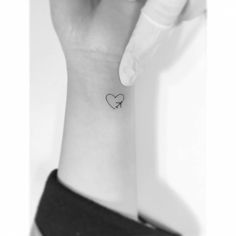 a woman's wrist with a small heart tattoo on the left side of her arm